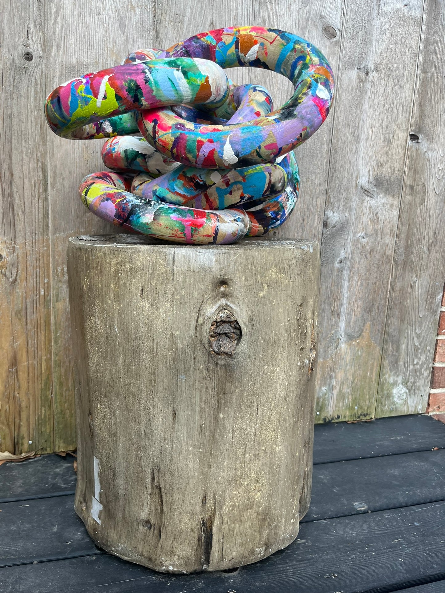 Hand-painted wooden chain links resting on a tree stump